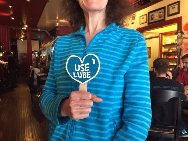 Woman holding Valentine heart sign reading "Use Lube"
